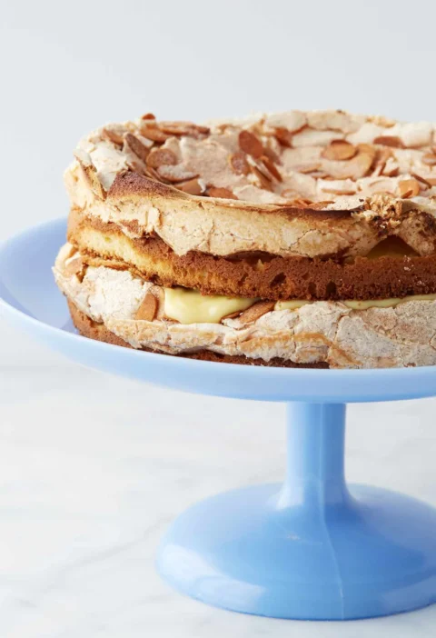 Martha Stewart Blitz Torte with almond meringue topping and pastry cream filling on a blue cake stand