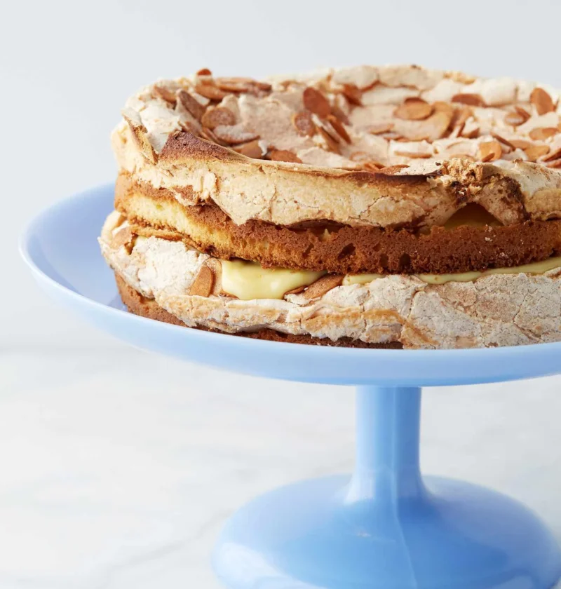 Martha Stewart Blitz Torte with almond meringue topping and pastry cream filling on a blue cake stand