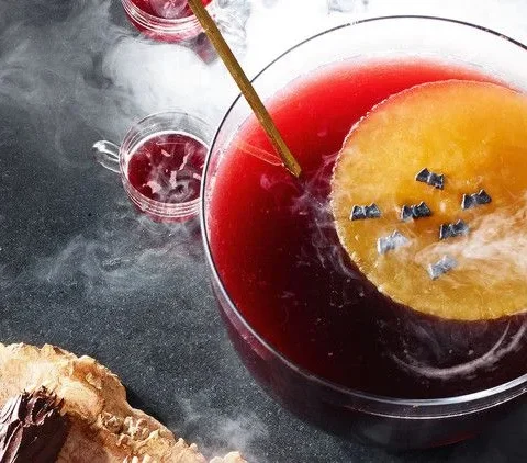 Martha Stewart Blood-Moon Punch with a frozen orange ice moon topped with candy bats floating in deep red punch