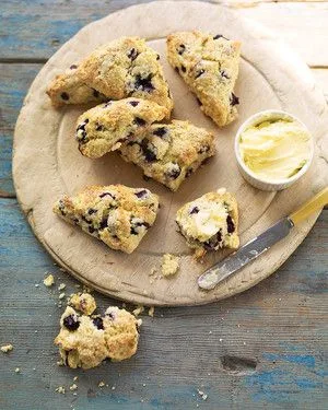 Martha Stewart blueberry-buttermilk scones on a wooden board with a small dish of butter and a butter knife