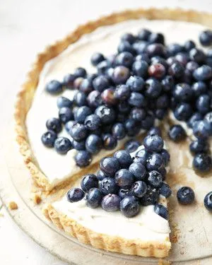 Martha Stewart blueberry-ricotta tart with fresh blueberries piled on a creamy ricotta filling in a golden crust, sliced on a wooden board