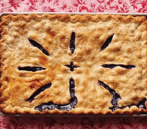 Martha Stewart blueberry slab pie with golden crust and vent slits showing blueberry filling on a rimmed baking pan
