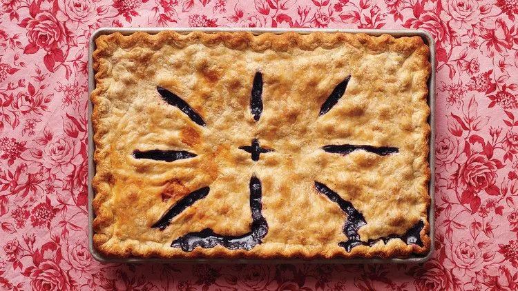 Martha Stewart blueberry slab pie with golden crust and vent slits showing blueberry filling on a rimmed baking pan