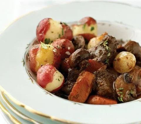 Martha Stewart boeuf bourguignon in a white bowl with beef chunks, carrots, mushrooms, pearl onions and red potatoes