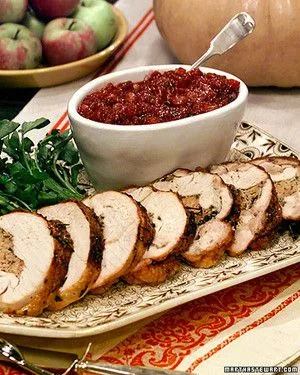 Martha Stewart boned, rolled, and tied turkey sliced on a platter with watercress and a bowl of cranberry compote