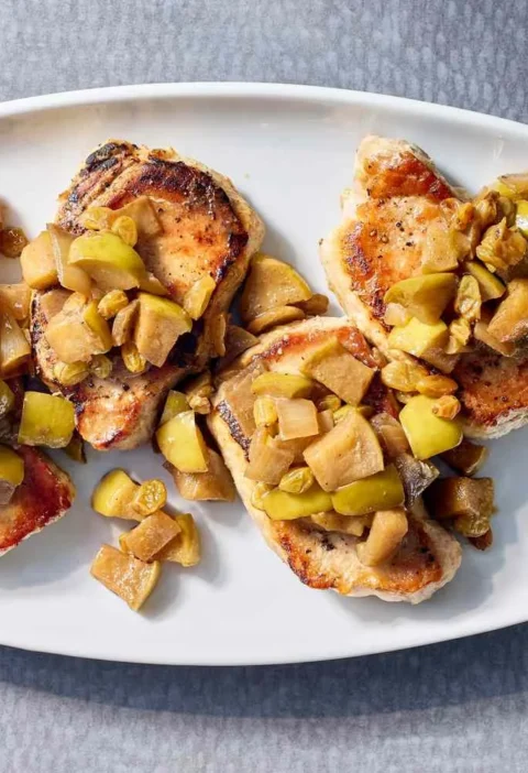 Martha Stewart boneless pork chops with apple chutney spooned over golden seared chops on a white platter