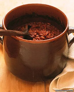 Martha Stewart Boston baked beans in a brown terra-cotta bean pot with a wooden spoon