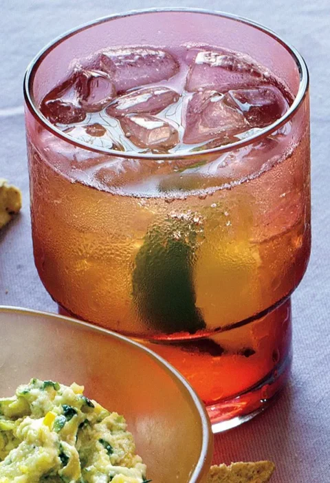 Martha Stewart bourbon and ginger cocktail over ice in a stacked amber glass with a lime wedge