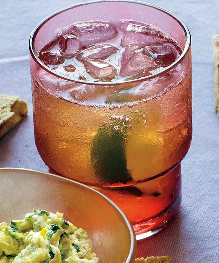 Martha Stewart bourbon and ginger cocktail over ice in a stacked amber glass with a lime wedge
