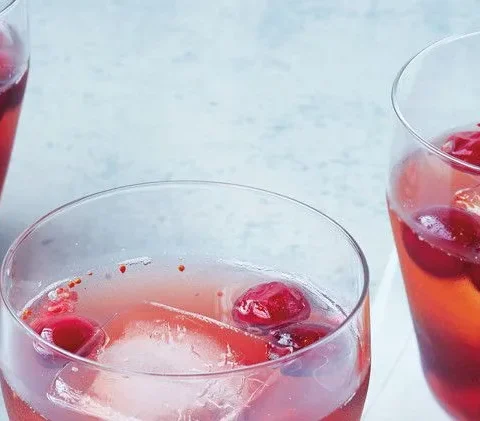 Martha Stewart bourbon-cranberry shrub cocktail in rocks glasses with ice and fresh cranberries