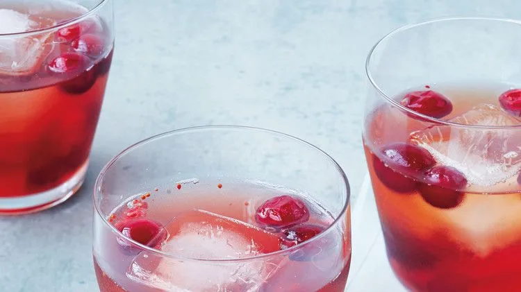 Martha Stewart bourbon-cranberry shrub cocktail in rocks glasses with ice and fresh cranberries