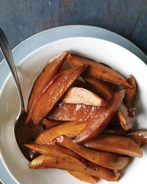 Martha Stewart bourbon sweet potatoes, glazed wedges served on a white plate with a spoon