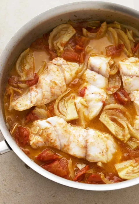 Martha Stewart braised fish with fennel and tomato, white fish fillets in a skillet of tomato fennel sauce