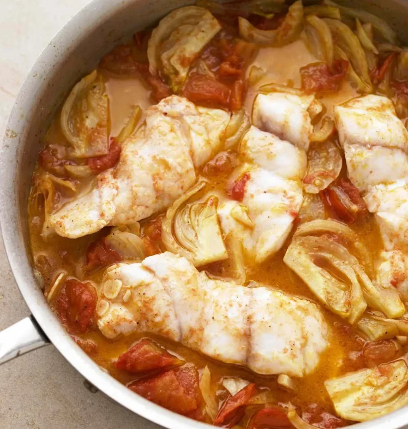 Martha Stewart braised fish with fennel and tomato, white fish fillets in a skillet of tomato fennel sauce