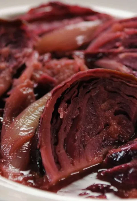 Martha Stewart braised red cabbage with caramelized apples and onion wedges in a glossy syrup on a white plate