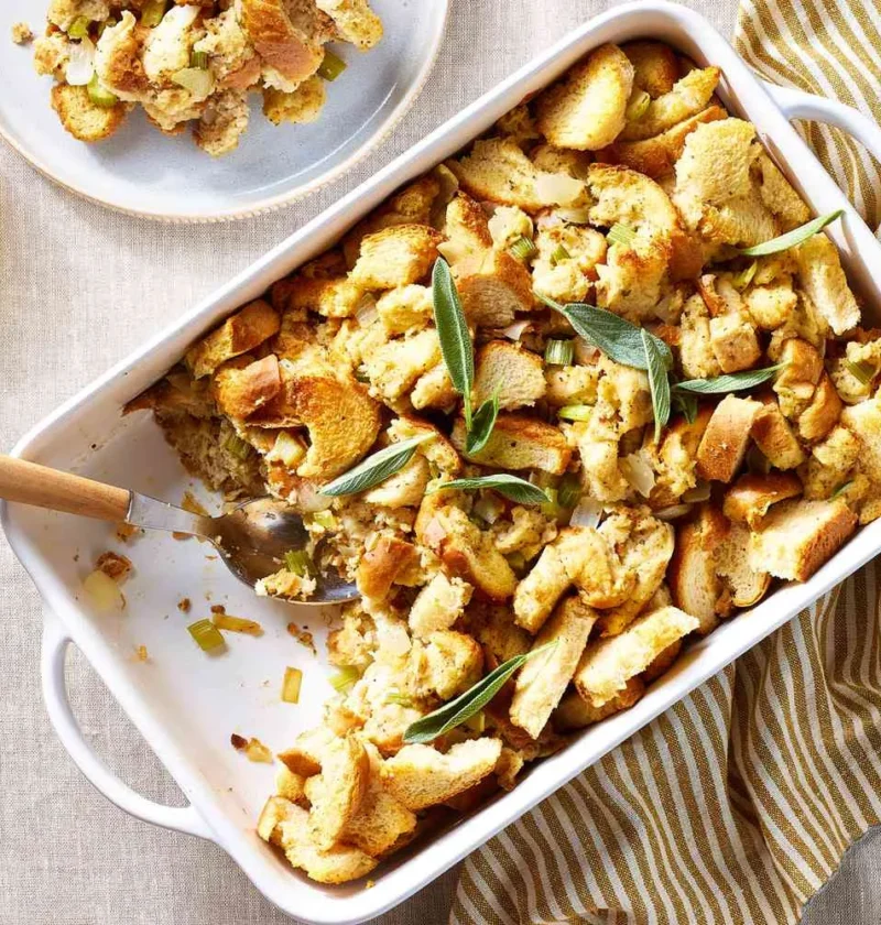 Martha Stewart bread stuffing with sage in a white baking dish with golden toasted bread cubes and fresh sage leaves
