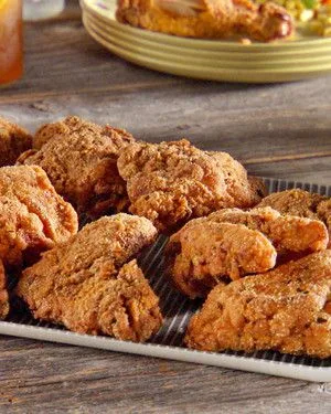 Martha Stewart brined and fried chicken pieces with a golden cornmeal crust on a wire rack
