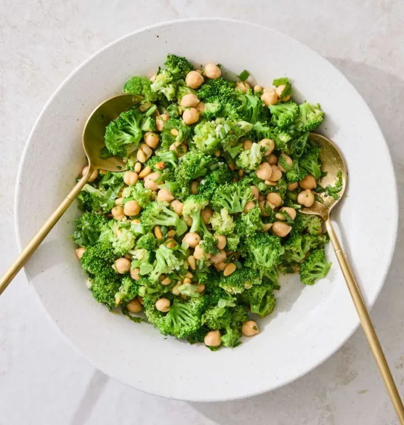Martha Stewart broccoli and chickpea salad in a white bowl with gold serving spoons