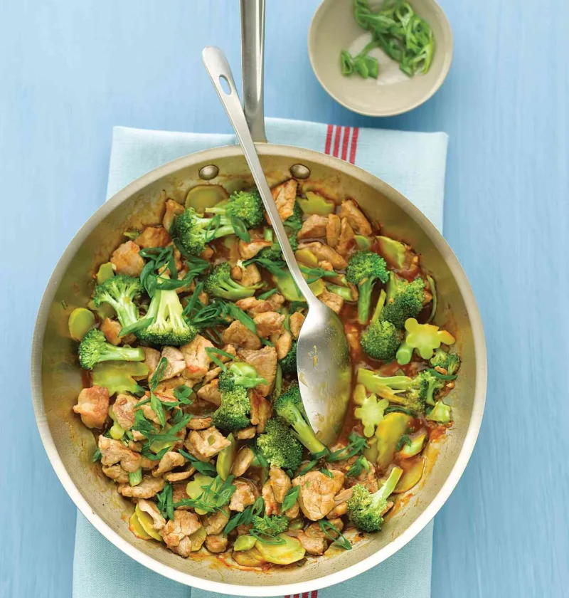 Martha Stewart broccoli and pork stir-fry in a stainless steel skillet with sliced scallions on top