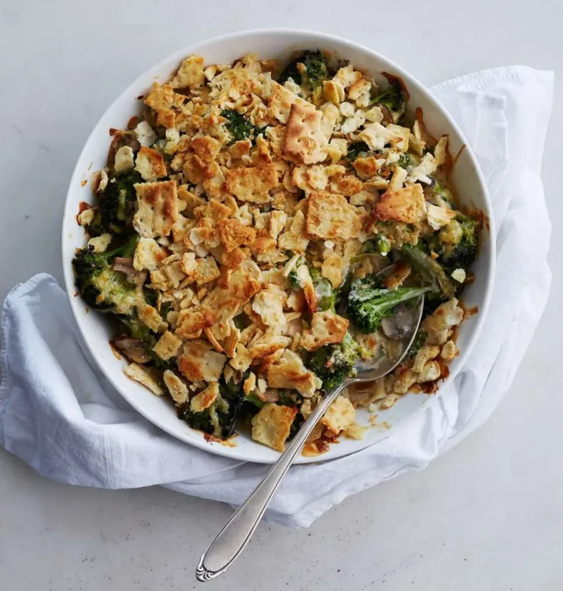 Martha Stewart broccoli cheese casserole with crackers in a white bowl, topped with golden crushed saltines and served with a spoon