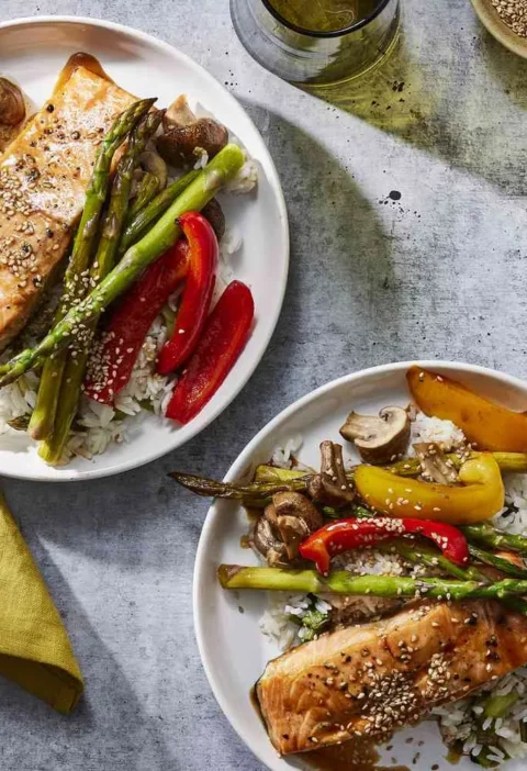 Martha Stewart broiled salmon with vegetables and scallion rice served on white plates with asparagus, bell peppers and mushrooms