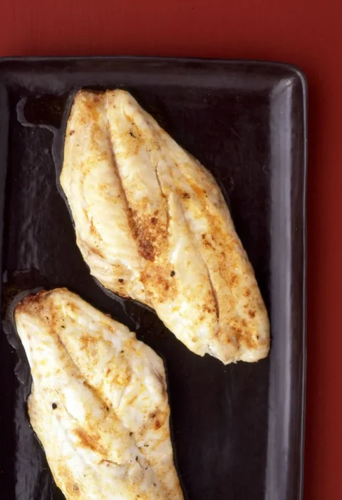 Martha Stewart broiled snapper with paprika butter, two golden browned fillets on a dark rectangular platter